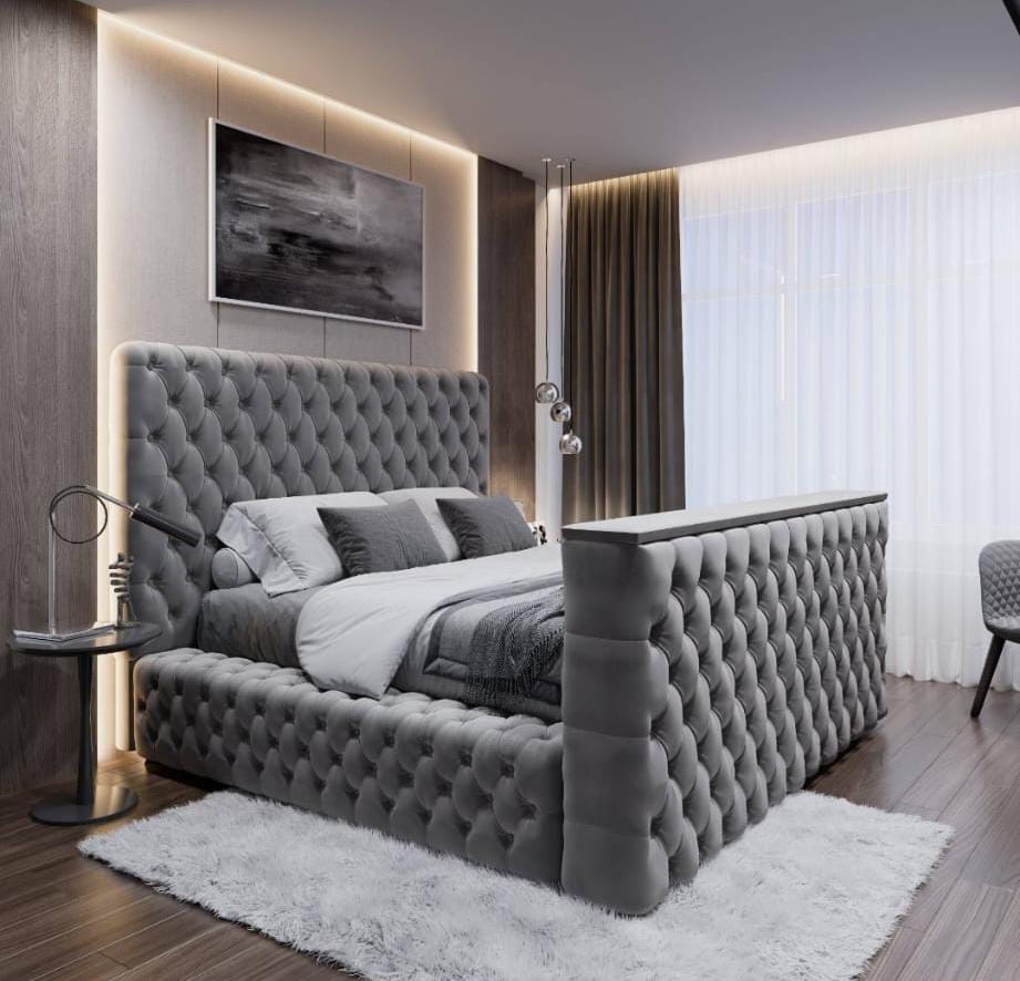 A luxurious gray tufted velvet royal tv bed with a high upholstered headboard and footboard fits king size tvs