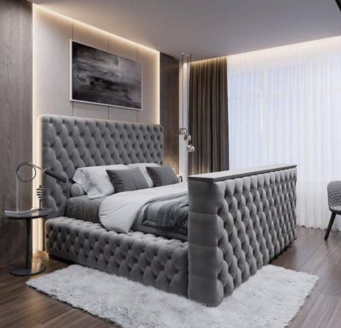 A luxurious gray tufted velvet royal tv bed with a high upholstered headboard and footboard fits king size tvs