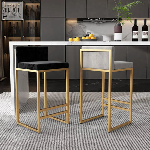 Two ruby bar stools with gold wrought iron frames, one black velvet and one light gray fabric, featuring high density cushions