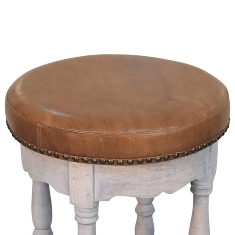 Rustic charm stool with brown leather top distressed white wooden base and brass nailhead trim for cozy seating
