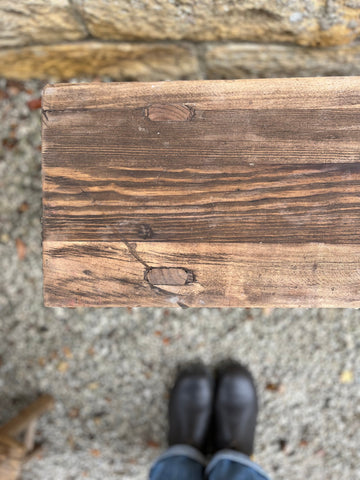 Rustic elm bench with a dark brown weathered finish and visible wood grain on a sturdy wooden frame
