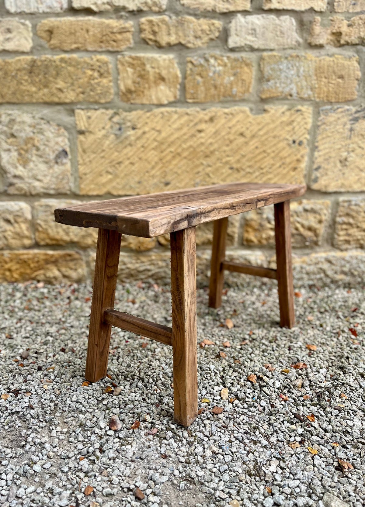 Rustic elm bench made of natural finish elm wood with simple sturdy construction and a rustic wooden look