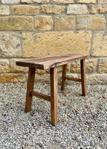 Rustic elm bench made of natural finish elm wood with simple sturdy construction and a rustic wooden look