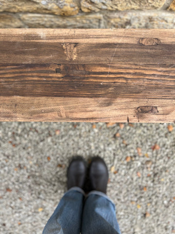 Rustic elm bench with a weathered dark brown finish and visible grain patterns on sturdy wooden seat