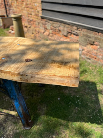 Rustic industrial kitchen island with light brown solid ash top and blue cast iron base outdoors