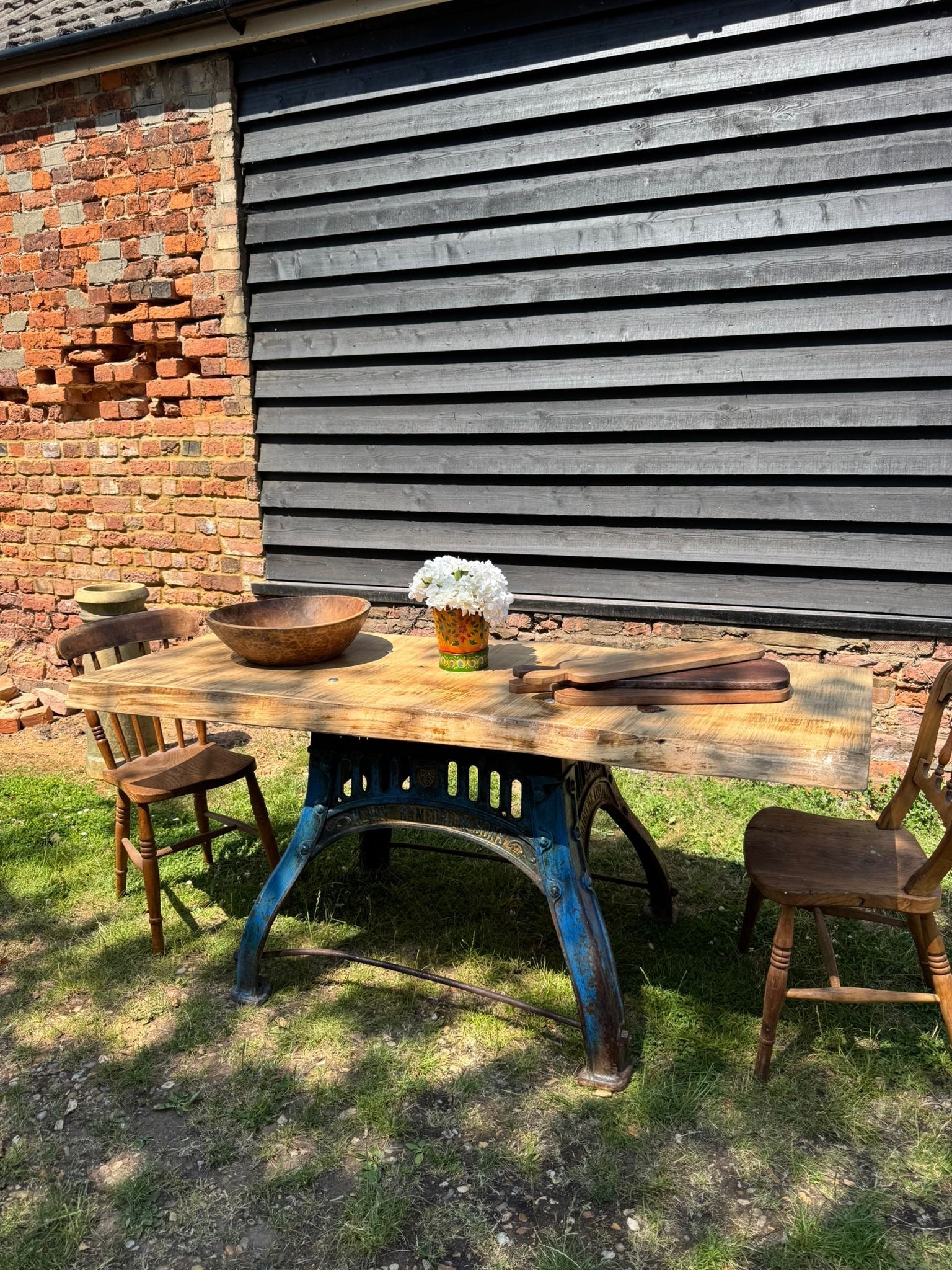Rustic industrial kitchen island with a blue cast iron base and solid ash top featuring bowl and white flowers on it
