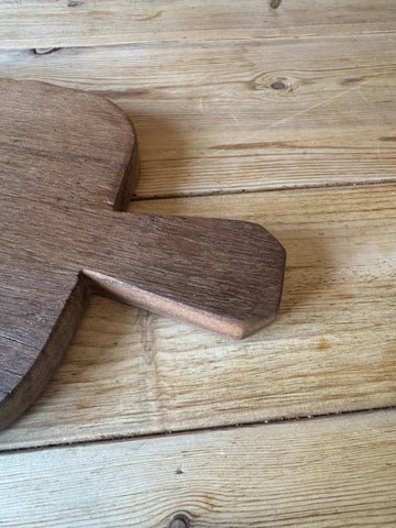 Dark brown wooden chopping board with smooth worn surface and rounded edges perfect for rustic cheese and charcuterie
