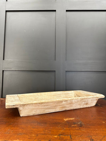 A rustic light-colored wooden bread loaf tray with weathered finish and visible grain for serving bread or antipasti