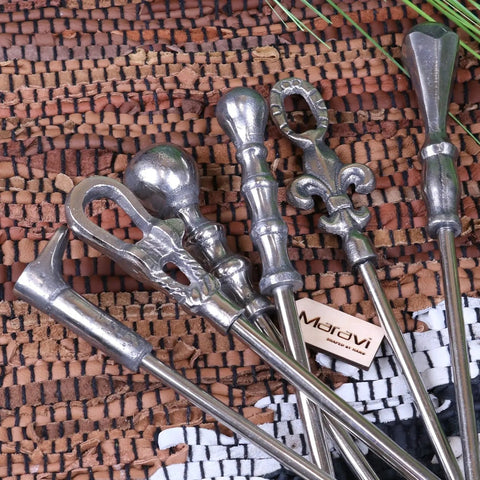 Set of ornate silver metal fireplace tools with fleur-de-lis handles shown alongside sagara long handled shoe horn with distressed finish