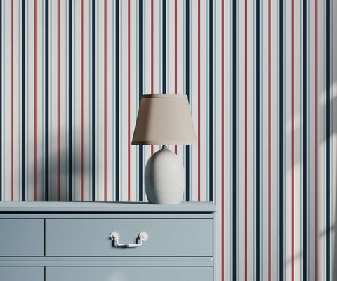 A sleek white ceramic table lamp with a beige fabric shade on a light blue dresser perfect for nautical stripe wallpaper decor