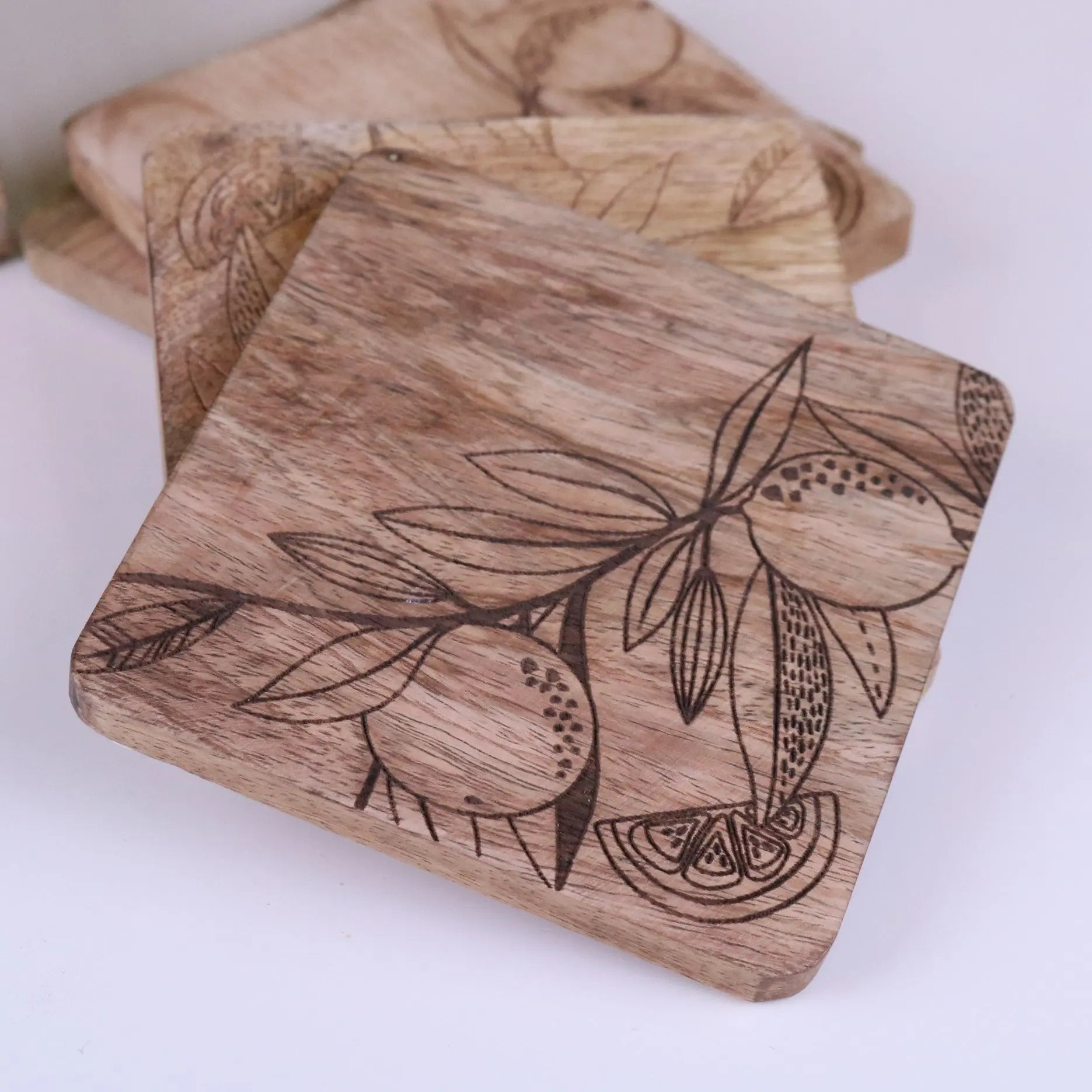 Square mango wood coasters with natural grain and dark engraved citrus design perfect for stylish drink protection