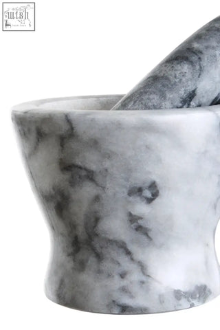 A sleek salerno grey marble curved mortar and pestle in gray and white marble with pestle resting inside