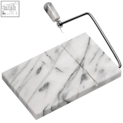 White marble cheese slicer with sleek metallic wire and handle on salerno white marble cheese board