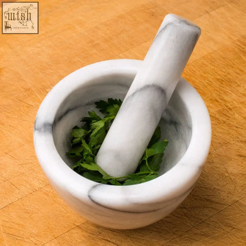 Salerno white marble mortar and pestle with gray veining containing fresh green herbs in a white marble mortar