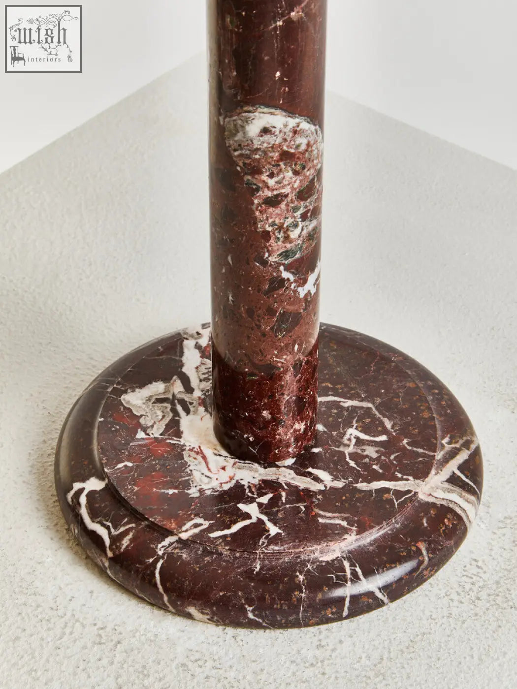 A polished dark brown marble salmo kitchen roll holder with swirling white and reddish veins on a circular base