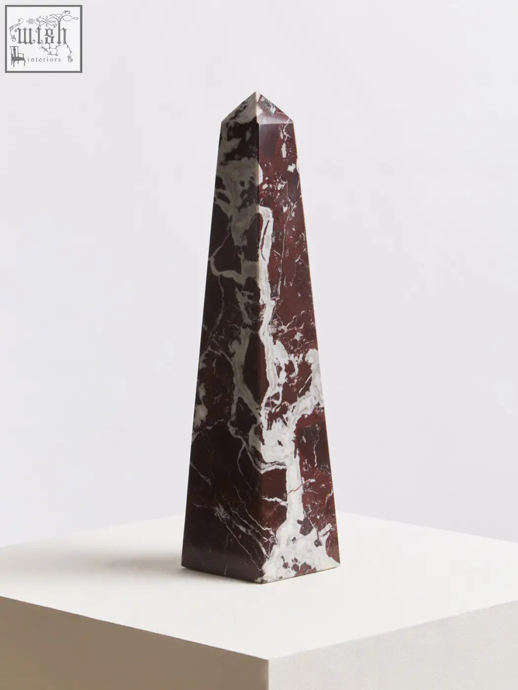 A sleek polished salmo large red marble obelisk with a pointed top in red and white marble design