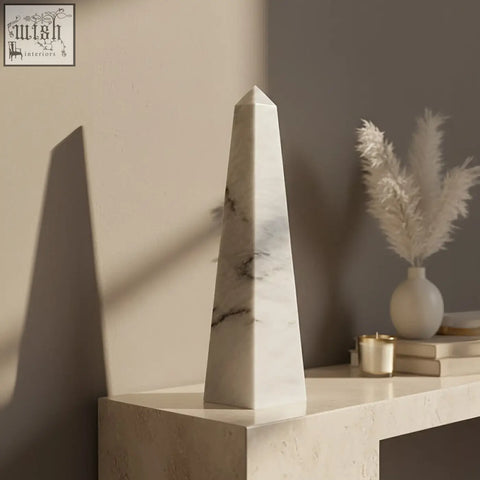 A sleek salmo large white marble obelisk with subtle gray veining on a minimalist console table
