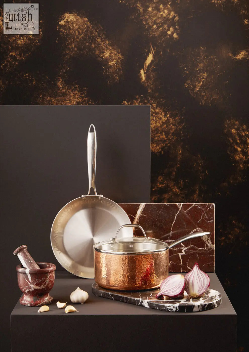 Copper pot with hammered finish and stainless steel handle on salmo oval black marble chopping board