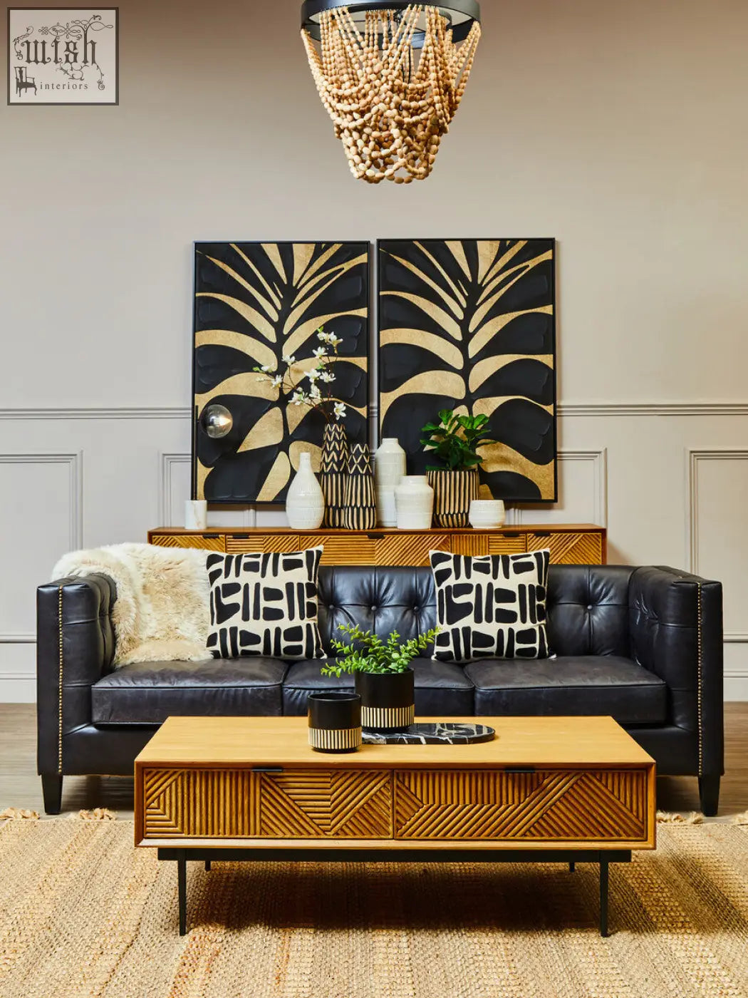 Salmo oval black marble chopping board displayed on black leather tufted sofa with silver nailhead trim and patterned pillows