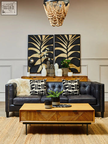 Salmo oval black marble chopping board displayed on black leather tufted sofa with silver nailhead trim and patterned pillows