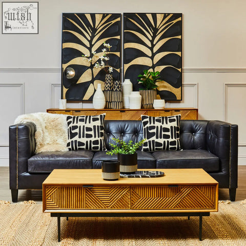 Black tufted leather sofa with nailhead trim and patterned pillows next to salmo oval black marble chopping board