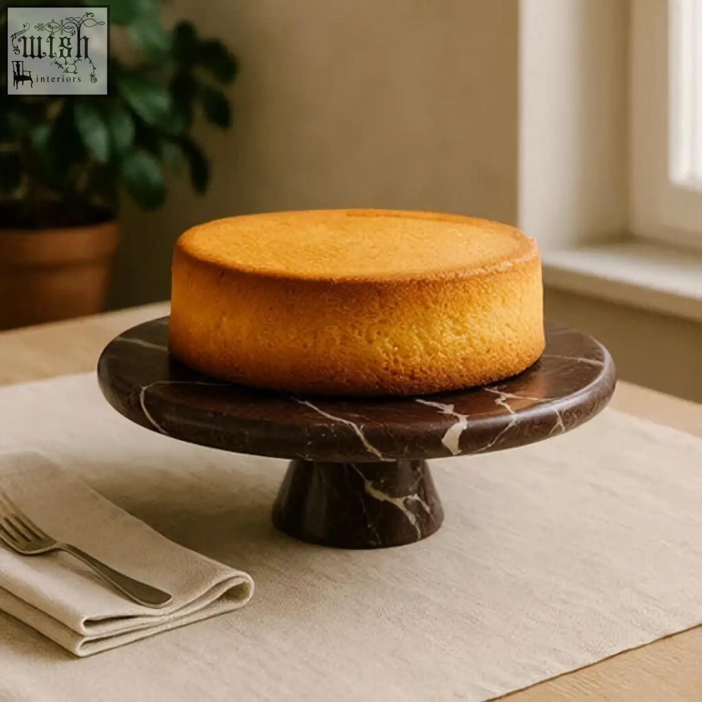 Golden brown sponge cake on a salmo red marble cake stand with a sleek dark red marble finish