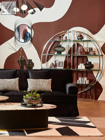 Black velvet sofa with geometric pillows next to three red marble tealight holders for cozy decor vibe