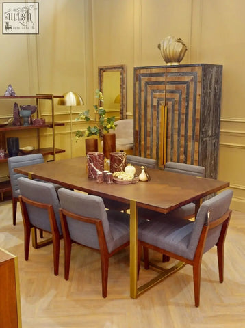 Modern dining set with a rich brown wooden table and six gray fabric chairs beside three red marble tealight holders