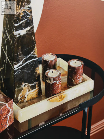Black and gold marble pyramid decorative object beside three red marble tealight holders for stylish decor
