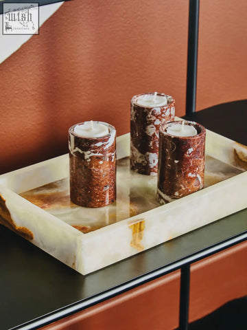 Three red marble tealight holders with a marbled brown and white pattern on an ornate off-white tray