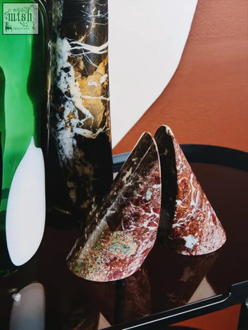 Two conical red marble bookends with white veins from salmo set of two on dark reflective surface