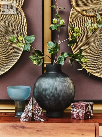 Dark gray textured ceramic vase with rounded body and narrow neck displayed with red marble bookends