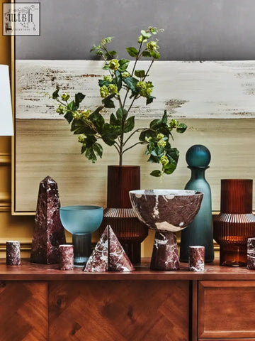 A tall slender vase with a dark brown textured surface shown with red marble bookends from the salmo set of two