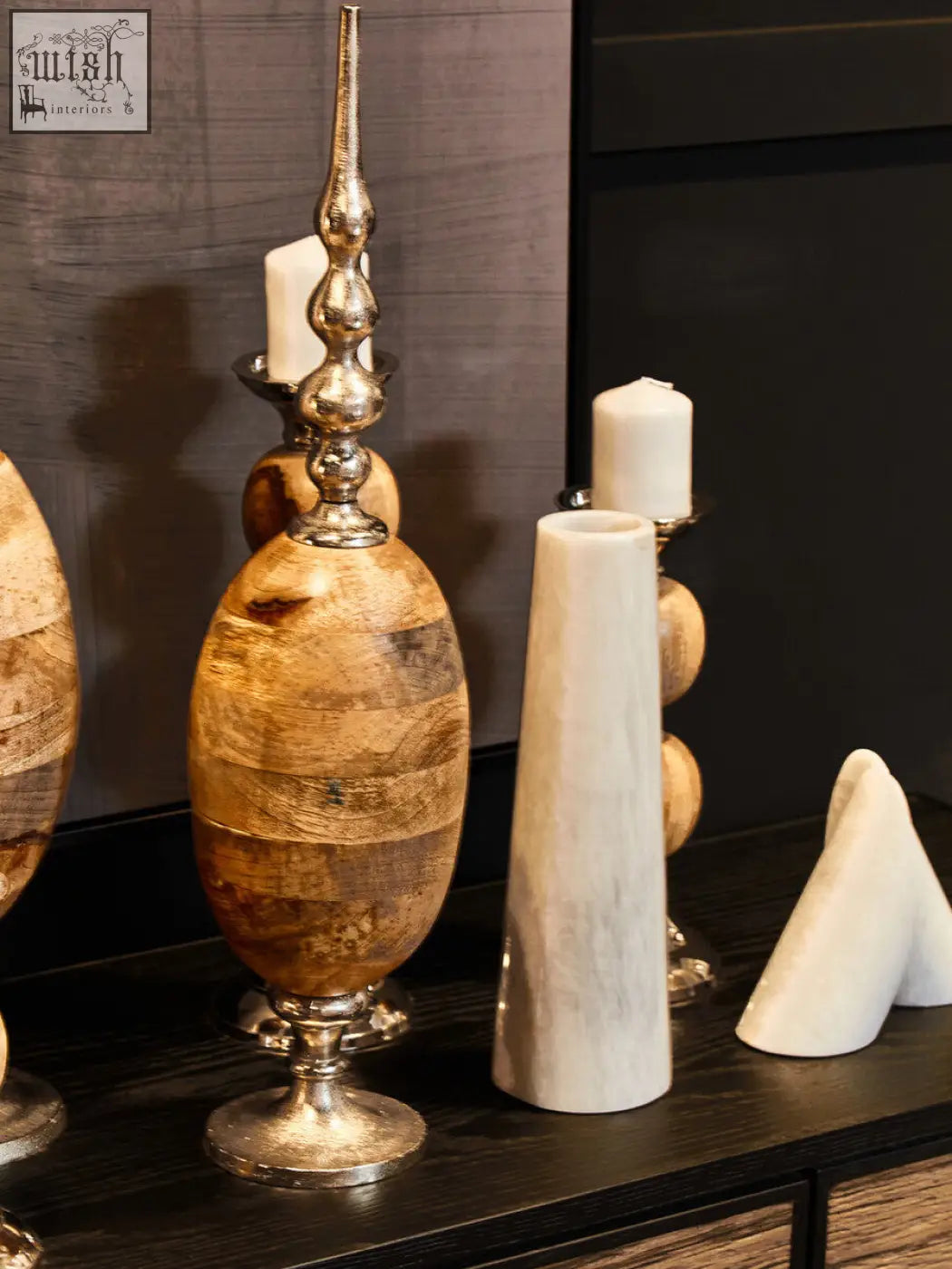 A tall slender wooden vase with silver spire and base next to the salmo set of two white marble bookends