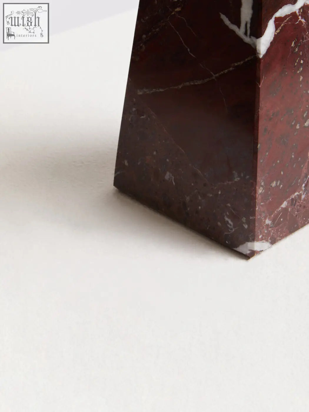 A sleek salmo small red marble obelisk with dark red color white veining and polished geometric design