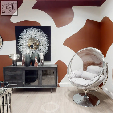 Transparent bubble chair with chrome frame and white cushioning next to the salmo small red marble obelisk centerpiece
