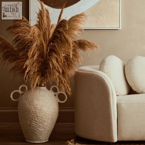 Off-white sanai cotton mache large vase with decorative handles holding dried pampas grass arrangement