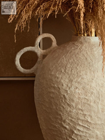 Off-white sanai cotton mache large vase with decorative interlocking ring handles holding dried pampas grass