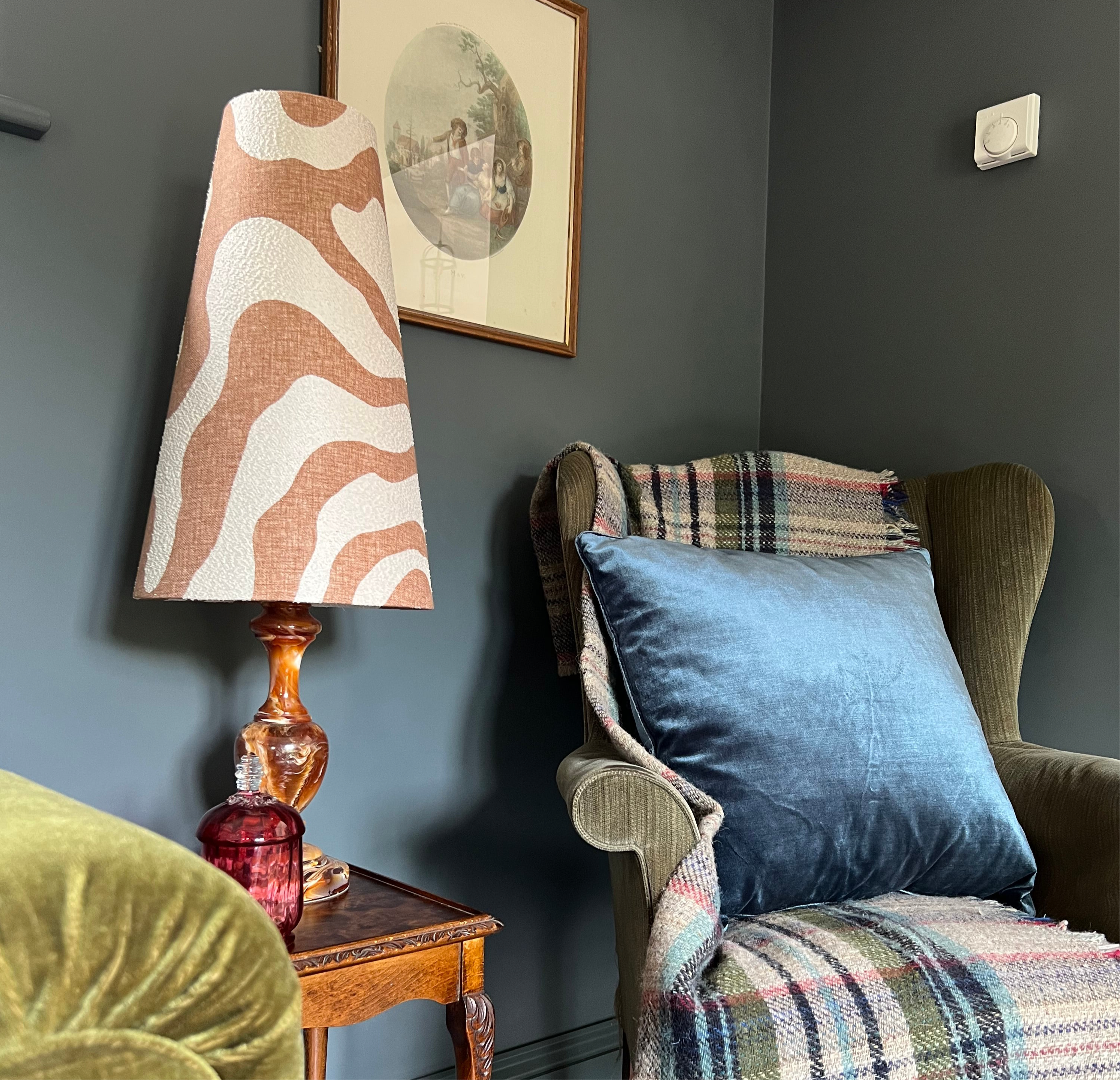 A sandstone wiggle extra tall lampshade with bold orange and cream zebra pattern on an ornate amber glass base