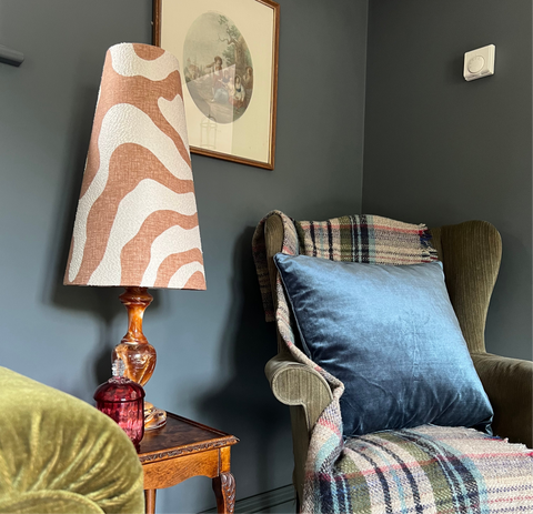 A sandstone wiggle extra tall lampshade with bold orange and cream zebra pattern on an ornate amber glass base