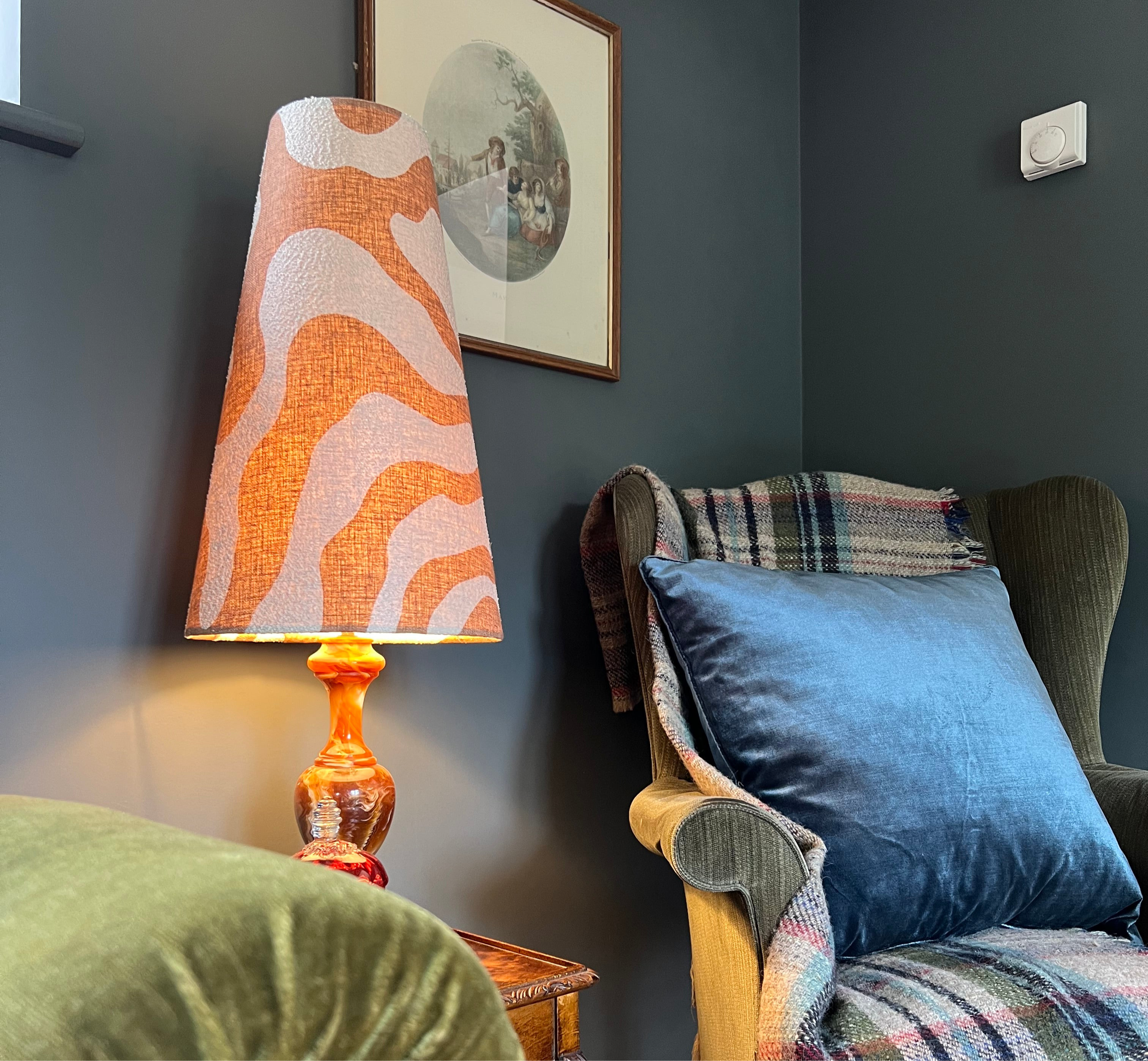 A vibrant orange and cream sandstone wiggle extra tall lampshade with textured fabric on amber glass base