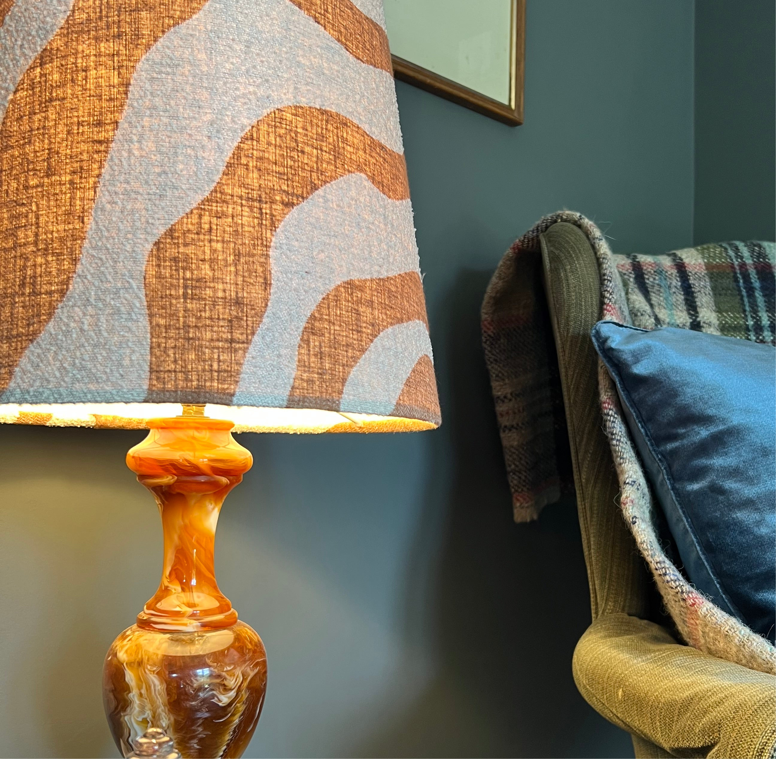 A warm amber glass lamp with a swirling base and an extra tall sandstone wiggle cone lampshade with abstract pattern