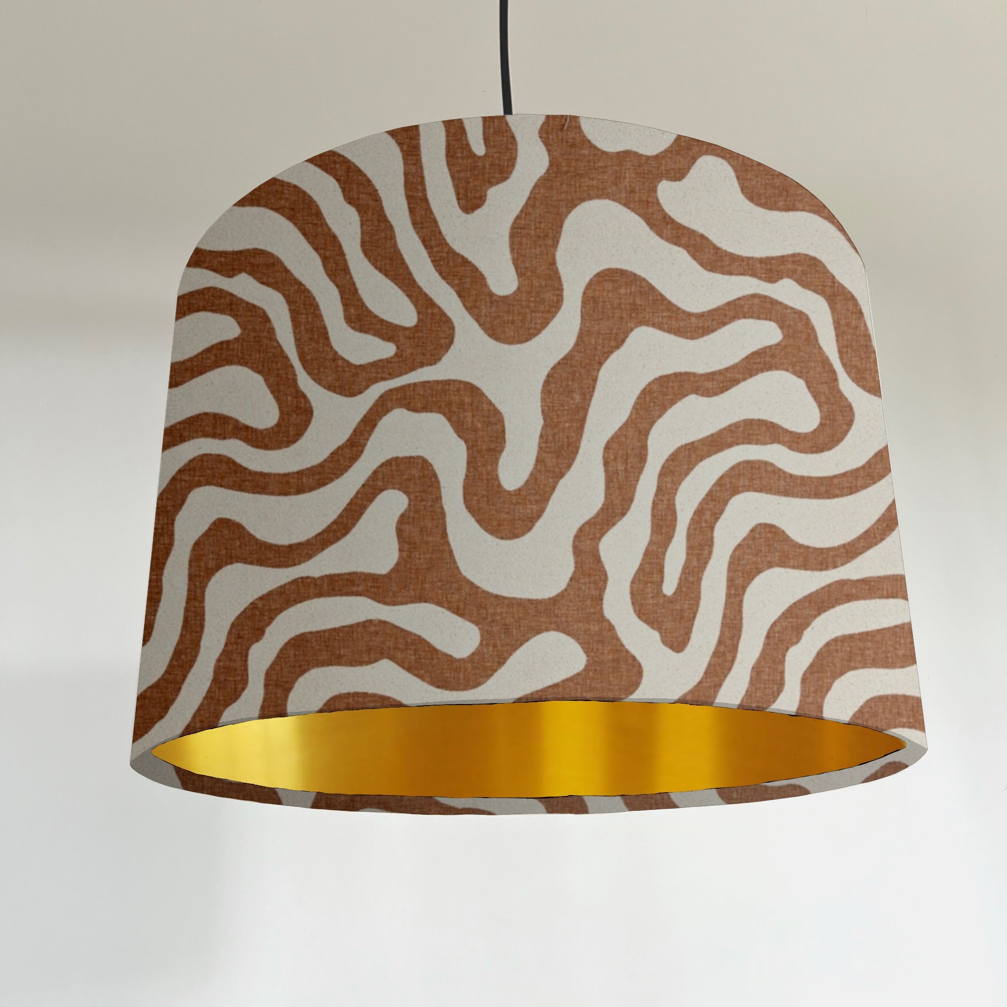 Cylindrical sandstone wiggle drum lampshade with bold brown white wavy pattern and metallic brushed gold lining interior