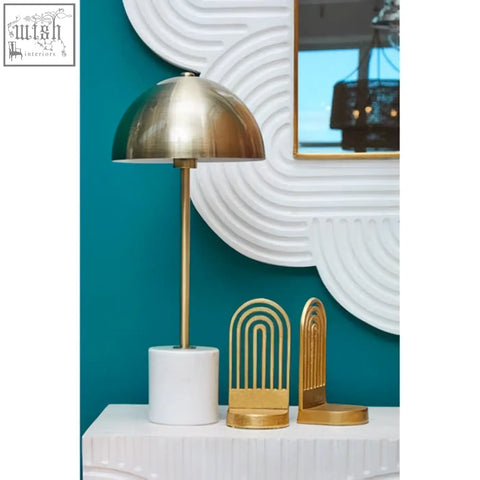 Gold-toned dome table lamp with slender stem and white marble base next to a mango wood wall mirror with white finish