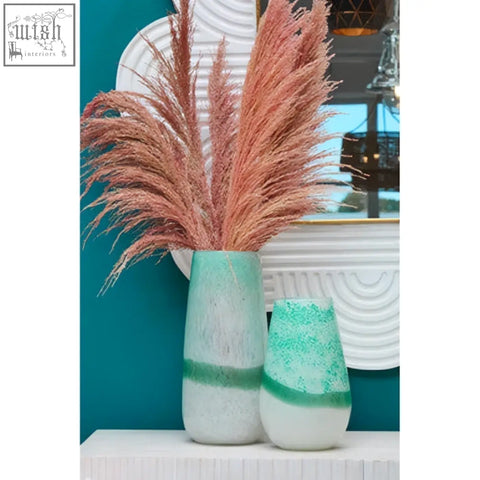 A tall slender vase with matte turquoise marbled finish and green stripe displayed beside a mango wood wall mirror