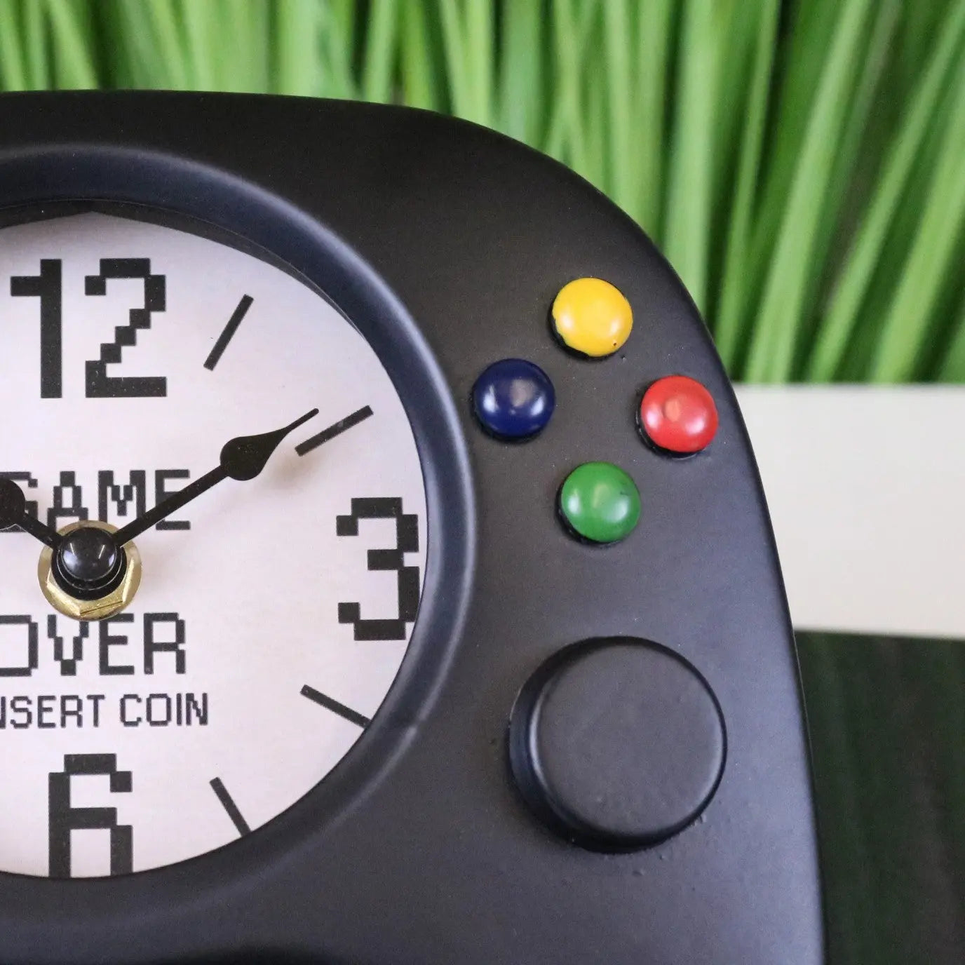 Black plastic game controller shaped gaming room clock with white face showing pixelated numbers and game over text