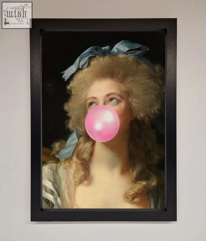 A sass queen framed print of a woman with blonde curls and a blue ribbon blowing a bright pink bubblegum bubble