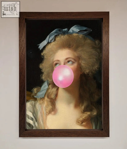 A sass queen framed print of a woman with curly blonde hair and a blue ribbon blowing a bright pink bubblegum bubble