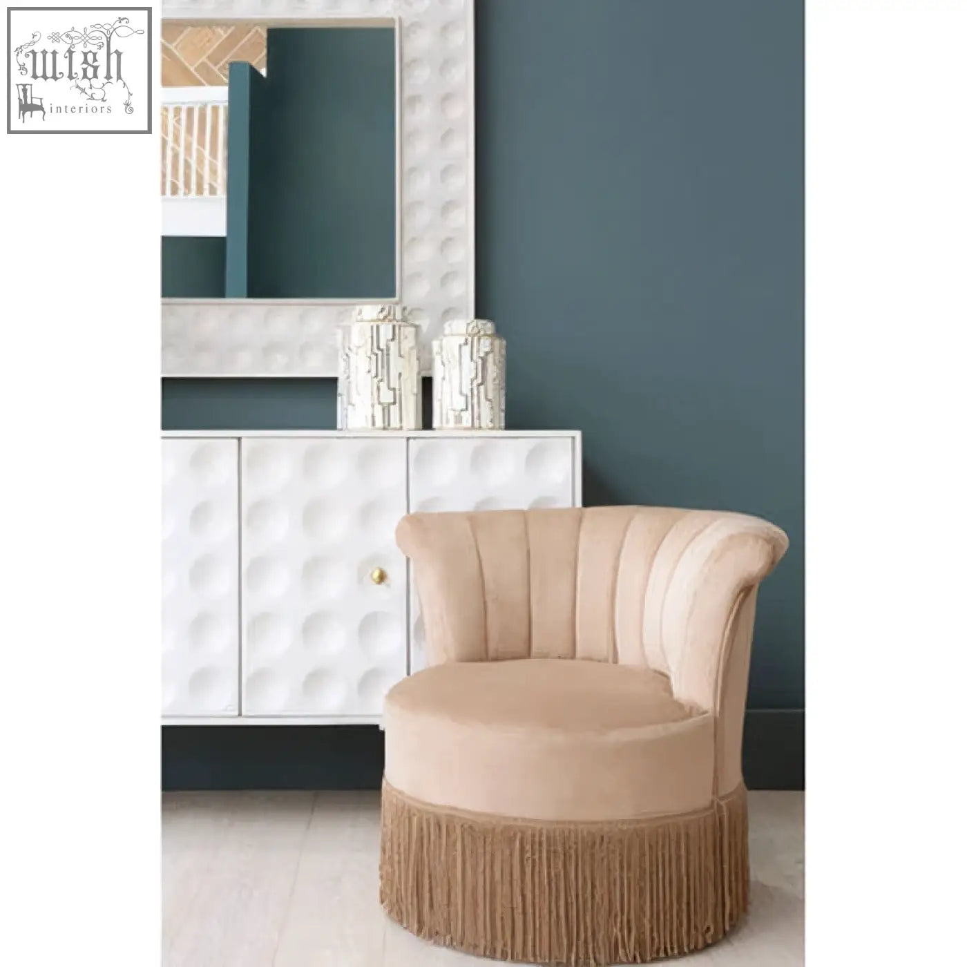 Beige velvet armchair with tufted back and fringed base shown next to satara wall mirror for stylish decor