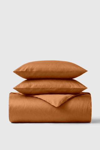 A soft rust-colored sateen duvet cover set with two matching pillows for a cozy comfy bed look